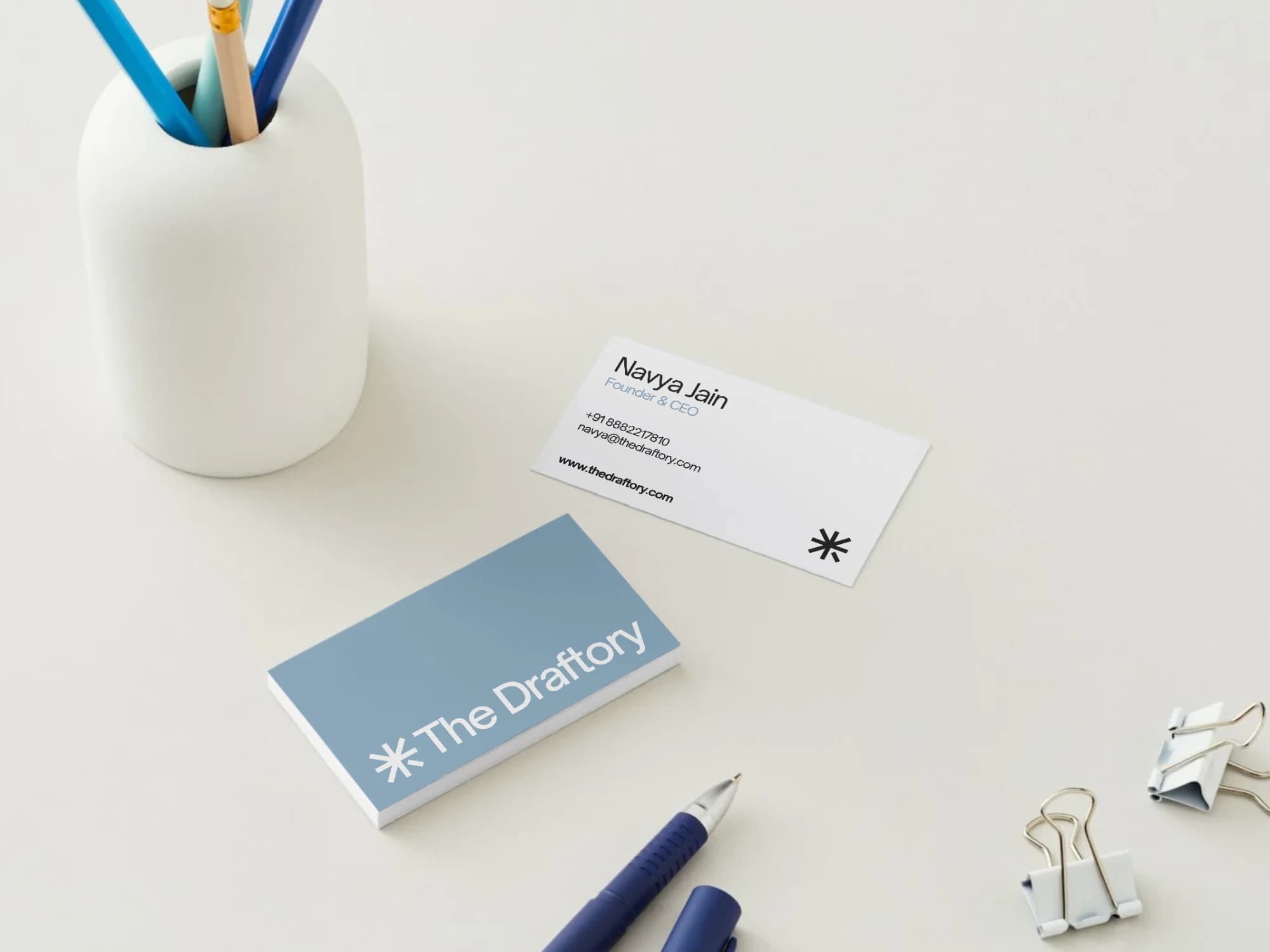 Dusty blue and white business cards designed for The Draftory, marked with an asterisk logo