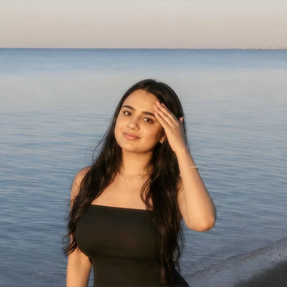 Navya Jain, founder of Outlier Labs, smiling by the sea at golden hour